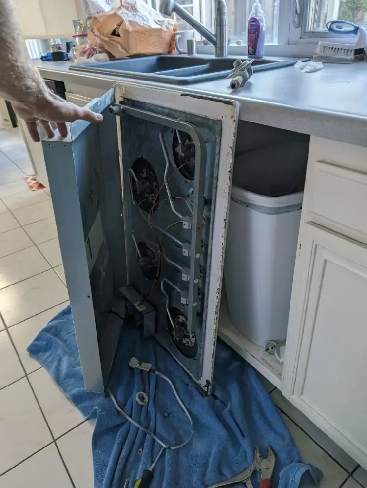 Built-in dishwasher pulled out from the cabinet for a leak and pump repair