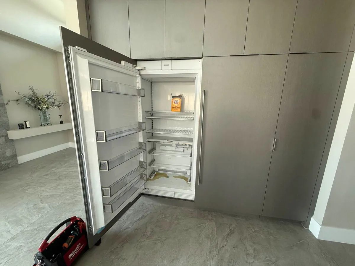 Integrated Sub-Zero refrigerator column behind custom panels in a modern Orange County home